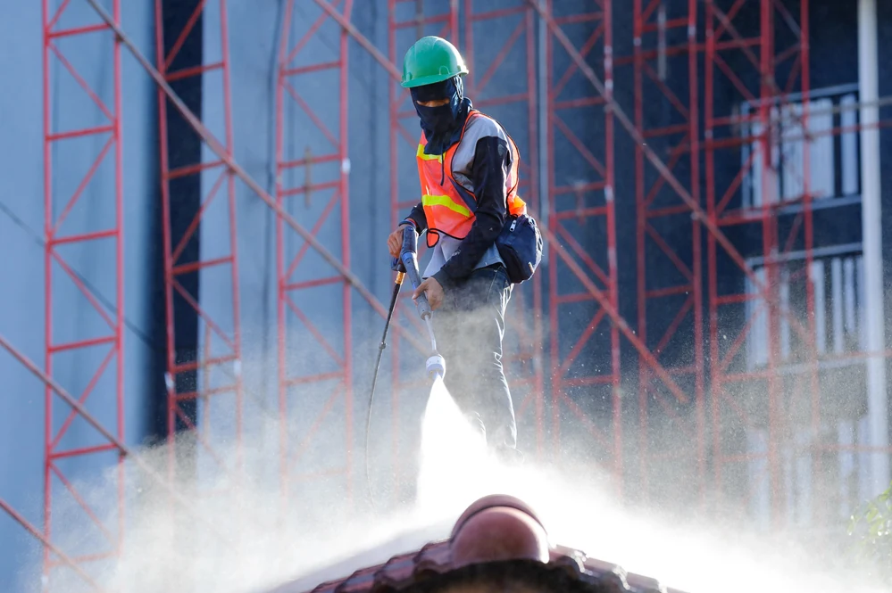 man using high pressure water to wash roof